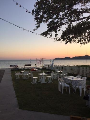 a group of tables and chairs next to the water at Kodtalay Resort in Chao Lao Beach