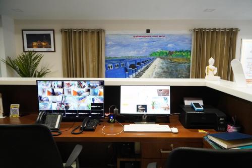 a desk with two monitors and a laptop and a phone at Hotel Jai's Inn in Thanjāvūr
