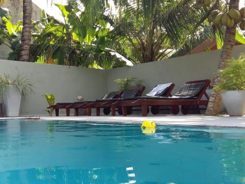 a pool with two chairs and a yellow ball in the water at Karl Holiday Bungalow in Kalutara