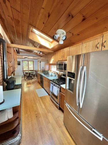 a kitchen with a stainless steel refrigerator and wooden cabinets at DOCKSIDE RETREAT LIMIT 14 home in North Sebago