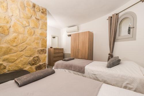 2 Betten in einem Zimmer mit einer Steinmauer in der Unterkunft Casa au Lilas Rosa in Benissa