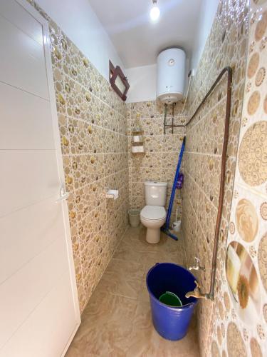 a bathroom with a toilet and a blue bucket at Dallas Surf Apartment in Agadir