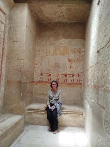 a woman sitting on a bench in a building with reliefs at Eyad Pyramids view in Cairo
