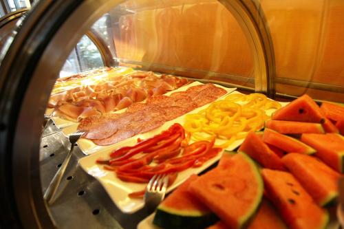 a buffet of food with vegetables and meat and fruit at Hotel Metrò in Milan
