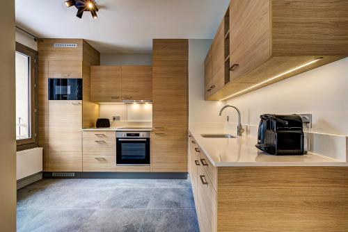 une cuisine avec des armoires en bois et un évier dans l'établissement White Pearl - Centre de Chamonix - 2ch - Renove, à Chamonix-Mont-Blanc