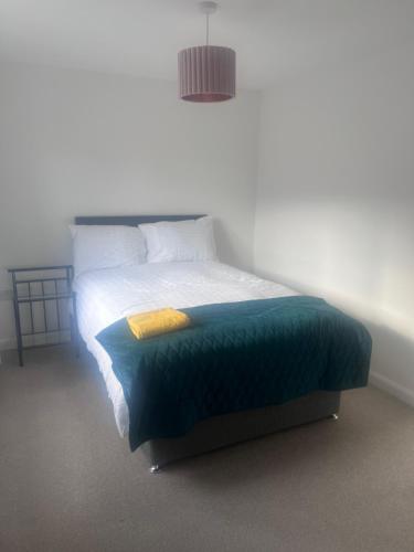 a bedroom with a bed with a green blanket at Market Harborough Guest House in Lubenham