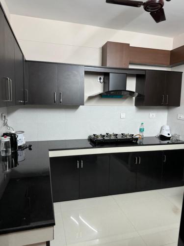 a kitchen with black cabinets and a black counter top at Aami dhivahi guest house in Trivandrum