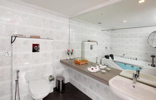 a bathroom with a toilet and a sink and a tub at Lake Palace Trivandrum in Vettutura