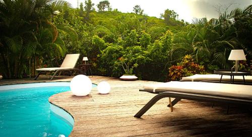 a pool with two chaise lounges on a wooden deck at La Villa Baie du Marin in Le Marin