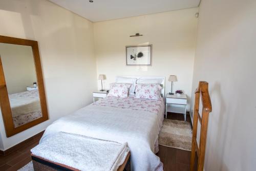 a bedroom with a white bed and a mirror at Barrocal Nature Houses in Nelas