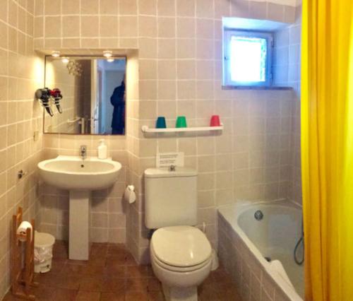 a bathroom with a toilet and a sink and a tub at La Casa Rossa in Marina di Bibbona