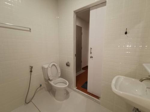 a white bathroom with a toilet and a sink at Ratanasiri Hotel in Chaiyaphum