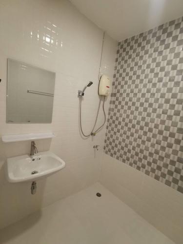 a white bathroom with a sink and a mirror at Ratanasiri Hotel in Chaiyaphum