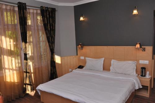 a bedroom with a large bed with white sheets at Hotel Ekant in Chail