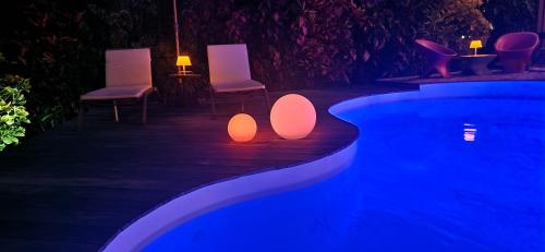a swimming pool with chairs and lights next to a swimming pool at La Villa Baie du Marin in Le Marin