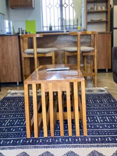 a wooden stool sitting on a rug in a room at Firefly Hill- a Cozy, one bedroom apartment in Kampala