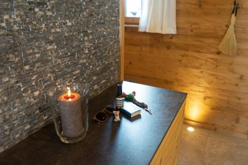 a candle and books on a table next to a brick wall at Chalet Frümsel in Wildhaus