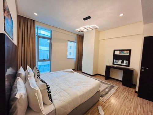a bedroom with a large bed and a television at Aspire Tower - One Bedroom Solo Haven Juffair in Manama