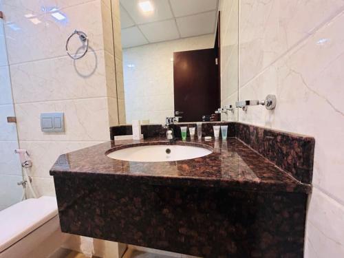 a bathroom with a sink and a mirror and a toilet at Aspire Tower - One Bedroom Solo Haven Juffair in Manama