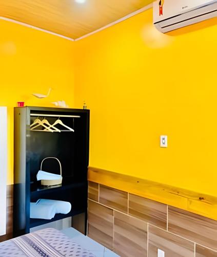 a room with a yellow wall and a shelf with a purse at Pousada Salinas de Atins in Atins