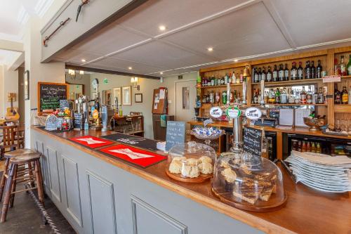 a bar in a pub with a counter and chairs at The Rose and Thistle Alwinton in Morpeth