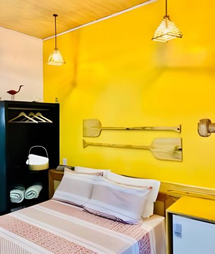a bedroom with a bed with a yellow wall at Pousada Salinas de Atins in Atins