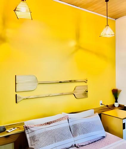 a room with a yellow wall with a bed and a desk at Pousada Salinas de Atins in Atins