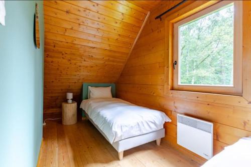 a bed in a log cabin with a window at Domaine la Clairière in Soultzmatt