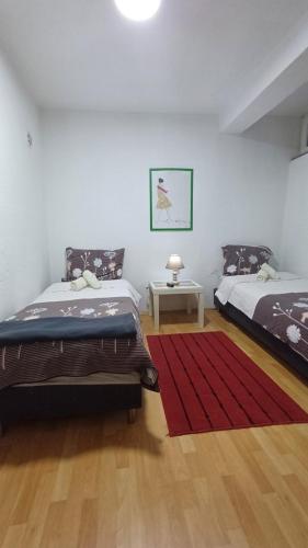 a bedroom with two beds and a red rug at Petrograd in Bitola