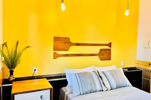 a bedroom with a yellow wall and a bed with white pillows at Pousada Salinas de Atins in Atins