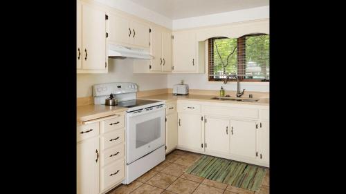 a kitchen with white cabinets and a sink at Harbor Guest House in Fish Creek