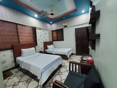 a bedroom with two beds and a desk and a tv at Diplomat Inn Hotel in Karachi