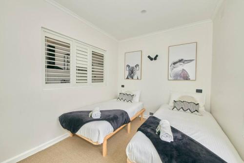 two beds in a room with white walls at Adorable beach shack in the heart of Aireys Inlet in Aireys Inlet