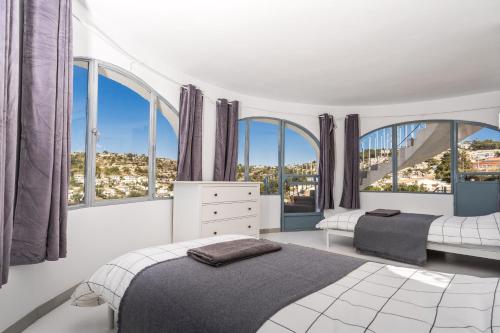 1 Schlafzimmer mit 2 Betten und großen Fenstern in der Unterkunft Beautiful Casa au Lilas Rosa, Benissa Costa in Benissa