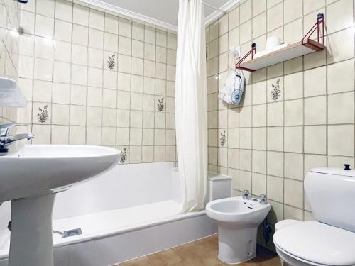 a bathroom with a sink and a tub and a toilet at Apartamentos Acuario in Denia