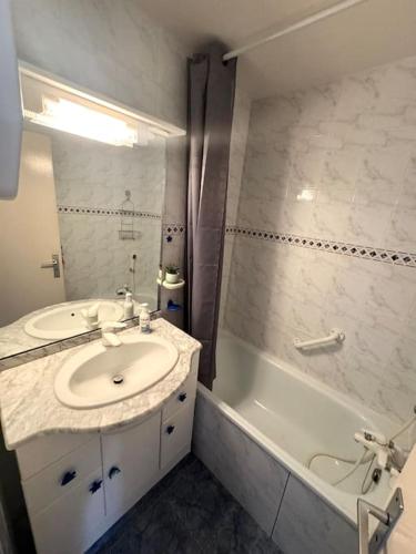 une salle de bain avec un lavabo et une baignoire dans l'établissement Appartement - Cap d'Agde, au Cap d'Agde