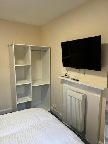a bedroom with a tv and shelves and a bed at Ye Olde Hotel in Leuchars
