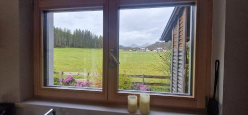 a window with two candles and a view of a field at Haus Alpengruss in Heiterwang