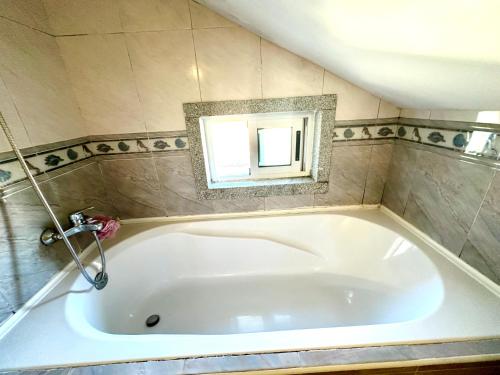 eine große weiße Badewanne im Bad mit Fenster in der Unterkunft Quarto em casa em Bragança, Parque eixo Atlântico in Bragança