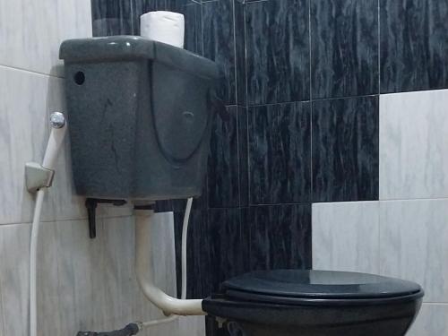 a bathroom with a black toilet with a roll of toilet paper at Green Leaves Holiday Home in Haputale