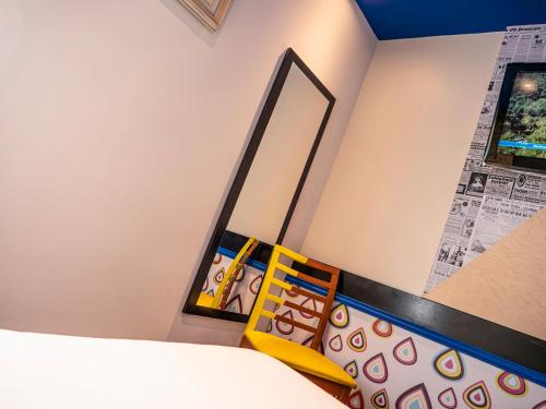 a bedroom with a yellow chair and a mirror at greet Hotel Marseille Provence Aéroport in Vitrolles