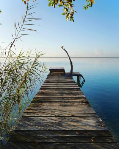 a wooden dock with a bench sitting on top of the water at Villa Santuario Lake front Oasis in Bacalar