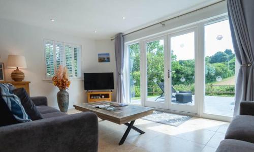 a living room with a couch and a table and a tv at Trewhiddle Retreat V9 by Together Travel - Luxury 4-Bedroom Villa in St Austell