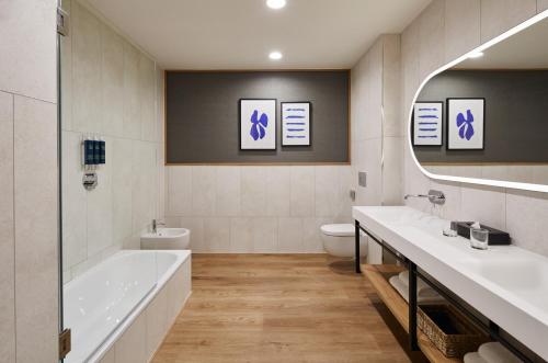 a bathroom with two sinks and a tub and a toilet at Four Points by Sheraton Barcelona Airport in Barcelona