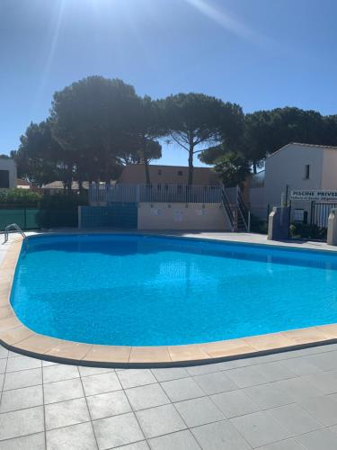 une grande piscine bleue avec des arbres en arrière-plan dans l'établissement Slyre, au Cap d'Agde