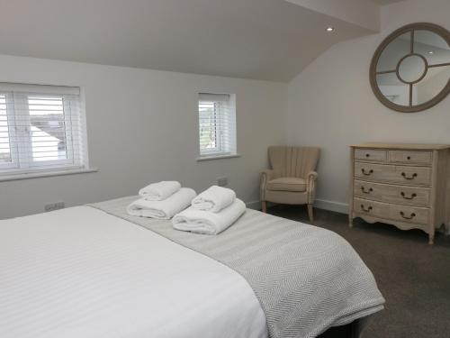a white bedroom with a bed and a dresser and a mirror at Edgemere Retreat in Grange Over Sands