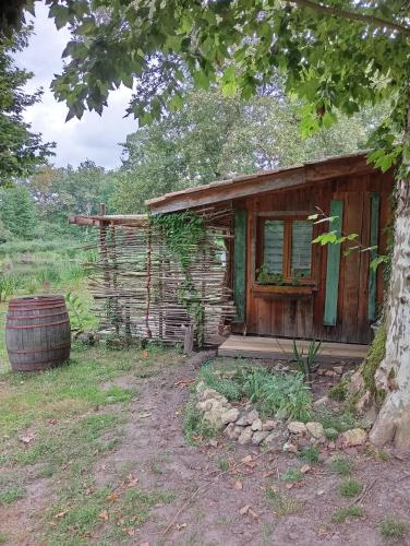 an old wooden house with a barrel in front of it at La maison du pêcheur in Saint-Justin