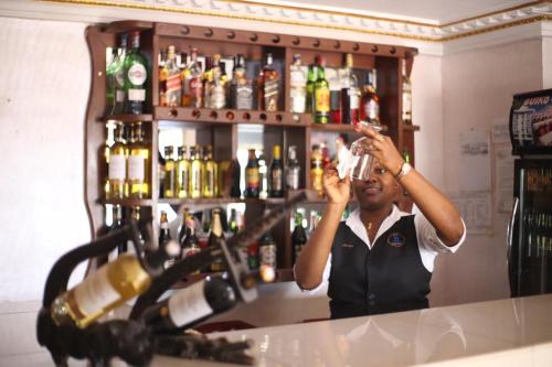 ヤウンデにあるHOTEL GUIKO Palaceの酒を飲みながら立っている男