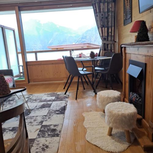 a living room with a table and chairs and a large window at STUDIO 2 ALPES STYLE CHALET au PIED DE TELESIEGE DU DIABLE in Les Deux Alpes