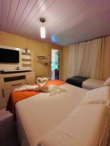 a hotel room with two beds and a tv at Pousada do Golfinho Fernando de Noronha in Fernando de Noronha